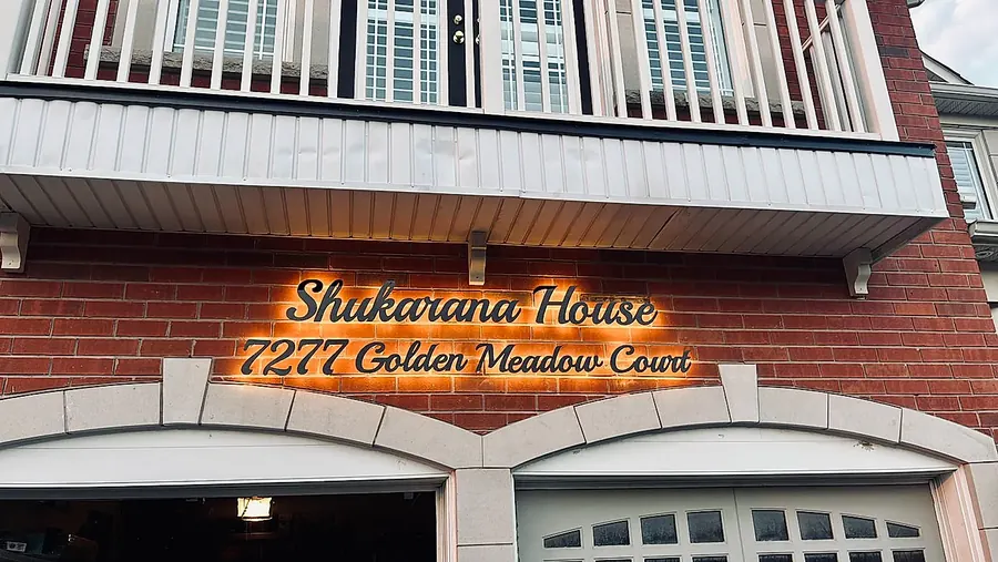 Shakarana House, 7277 Golden Meadow Court, lit under a brick arch