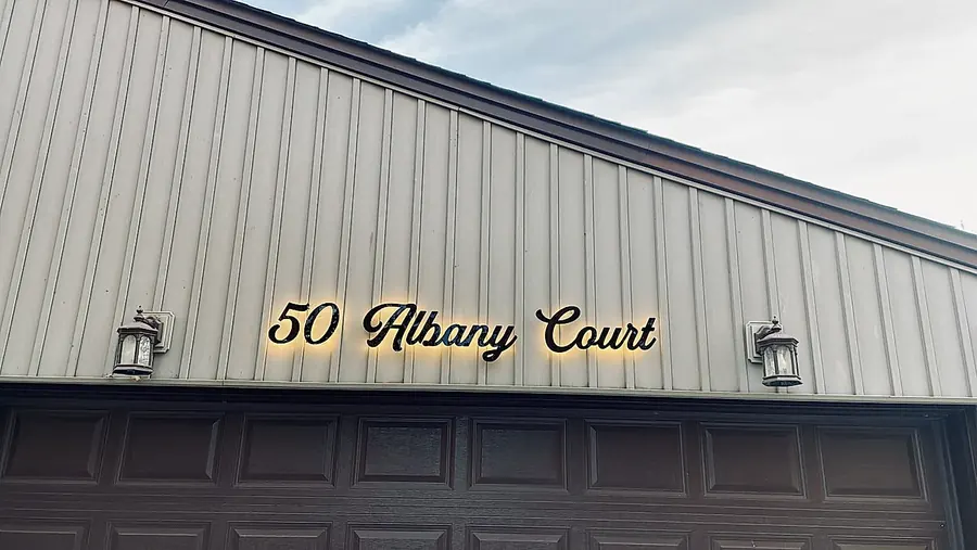 50 Albany Court lit between two lanterns on metal siding